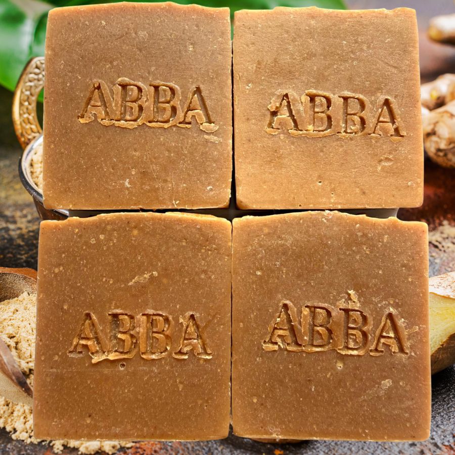 Cuatro barras cuadradas de jabón artesanal ABBA dispuestas en una cuadrícula de 2x2. Las pastillas son de un cálido color marrón tierra y llevan el nombre de la marca "ABBA" grabado en relieve en el centro de cada una.