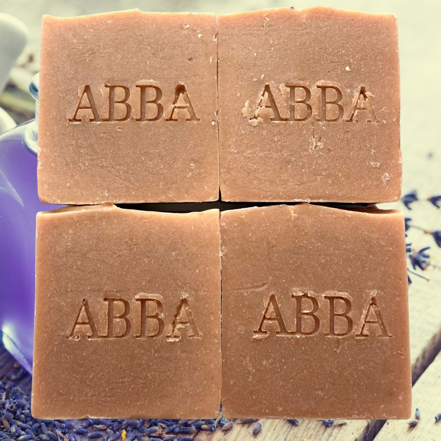 Cuatro barras rectangulares de jabón artesanal ABBA dispuestas en una cuadrícula de 2x2. El jabón es de un cálido color marrón terracota, con el nombre de la marca "ABBA" grabado en relieve en el centro de cada pastilla.